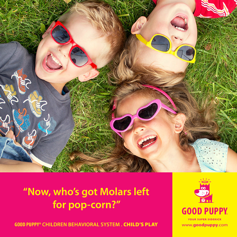 The image shows three children lying on grass, laughing and wearing colorful sunglasses. Below the image, a yellow and pink section features the text: "Now, who's got Molars left for popcorn?" It also mentions "GOOD PUPPY® CHILDREN BEHAVIORAL SYSTEM. CHILD'S PLAY" and provides the website "www.goodpuppy.com." The Good Puppy logo and character are displayed on the right side.